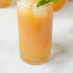 Earl Grey lemonade in a tall glass garnished with fresh orange and mint