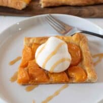 Puff pastry square topped with sliced apricots, whipped cream and caramel sauce