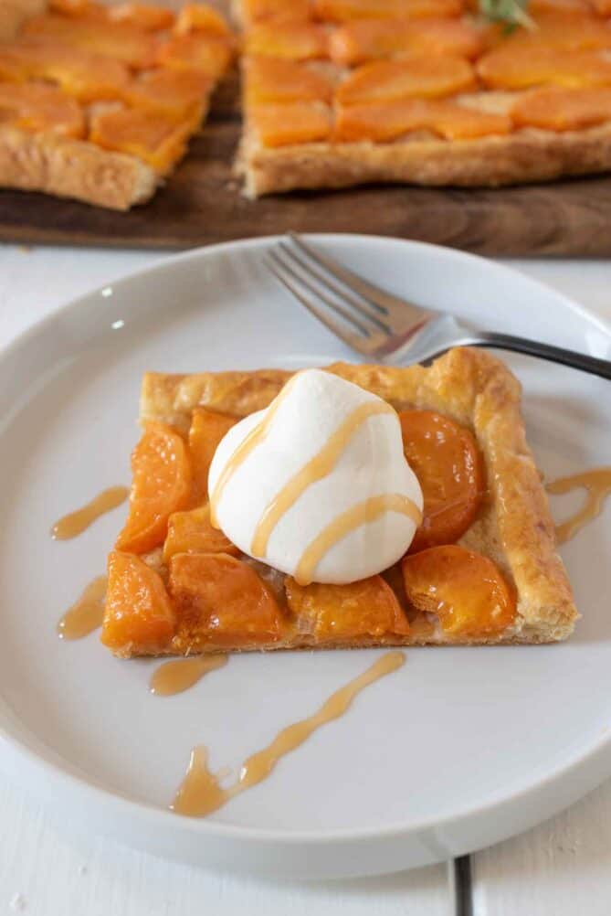 Puff pastry square topped with sliced apricots, whipped cream and caramel sauce