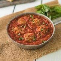 A pan of easy chicken meatballs in marinara sauce garnished with fresh basil
