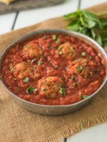 A pan of easy chicken meatballs in marinara sauce garnished with fresh basil