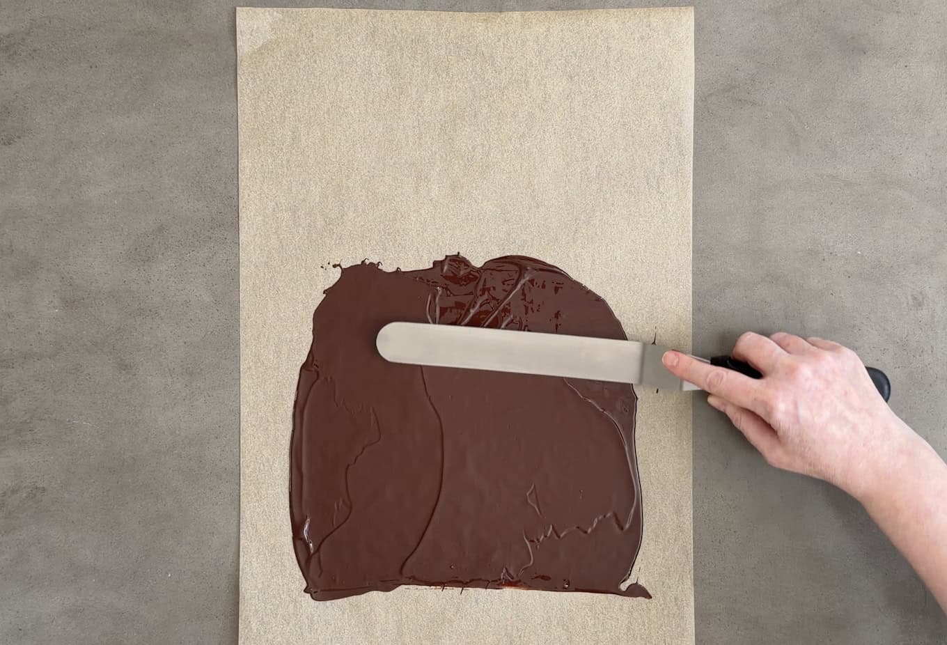 Spreading melted chocolate onto parchment paper