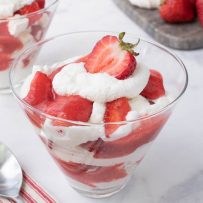 A glass bowl filled with meringue, whipped cream and strawberries
