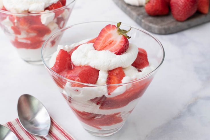 A glass bowl filled with meringue, whipped cream and strawberries