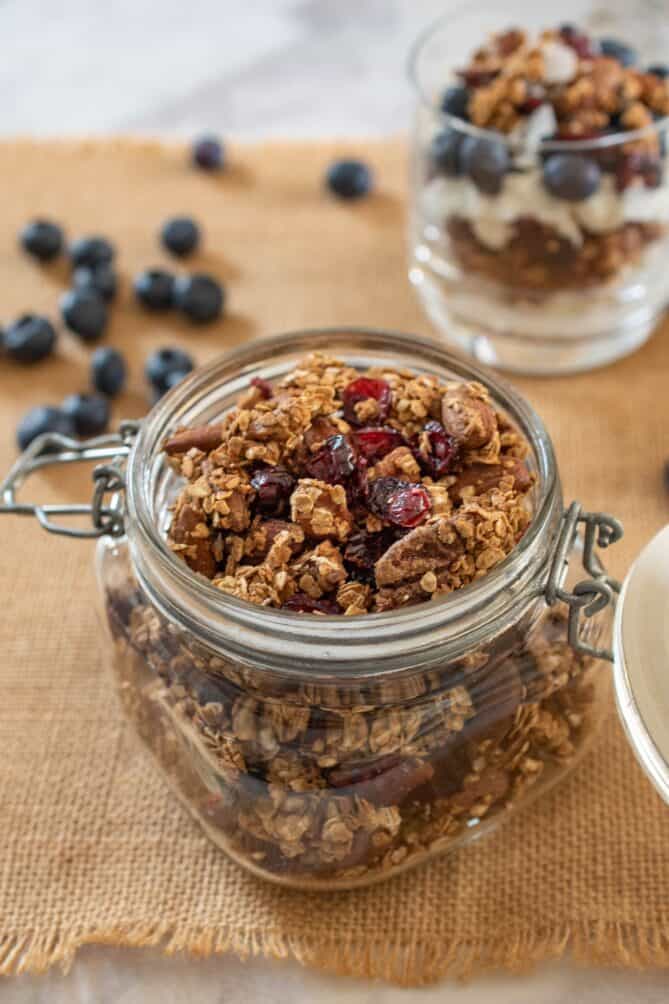 A glass jar filled with crunch granola mixed with dried cranberries