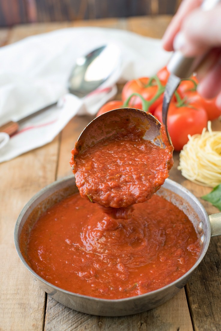 Marinara sauce being ladled into a pan