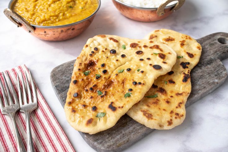Browned naan bread garnished with cilantro