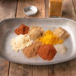 A grey bowl with small piles of different color spices