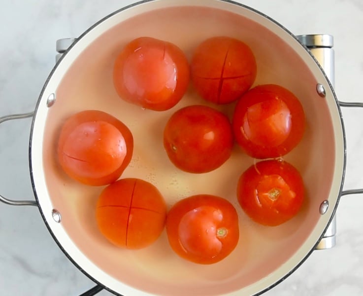 Tomatoes in simmering water to help remove the skins