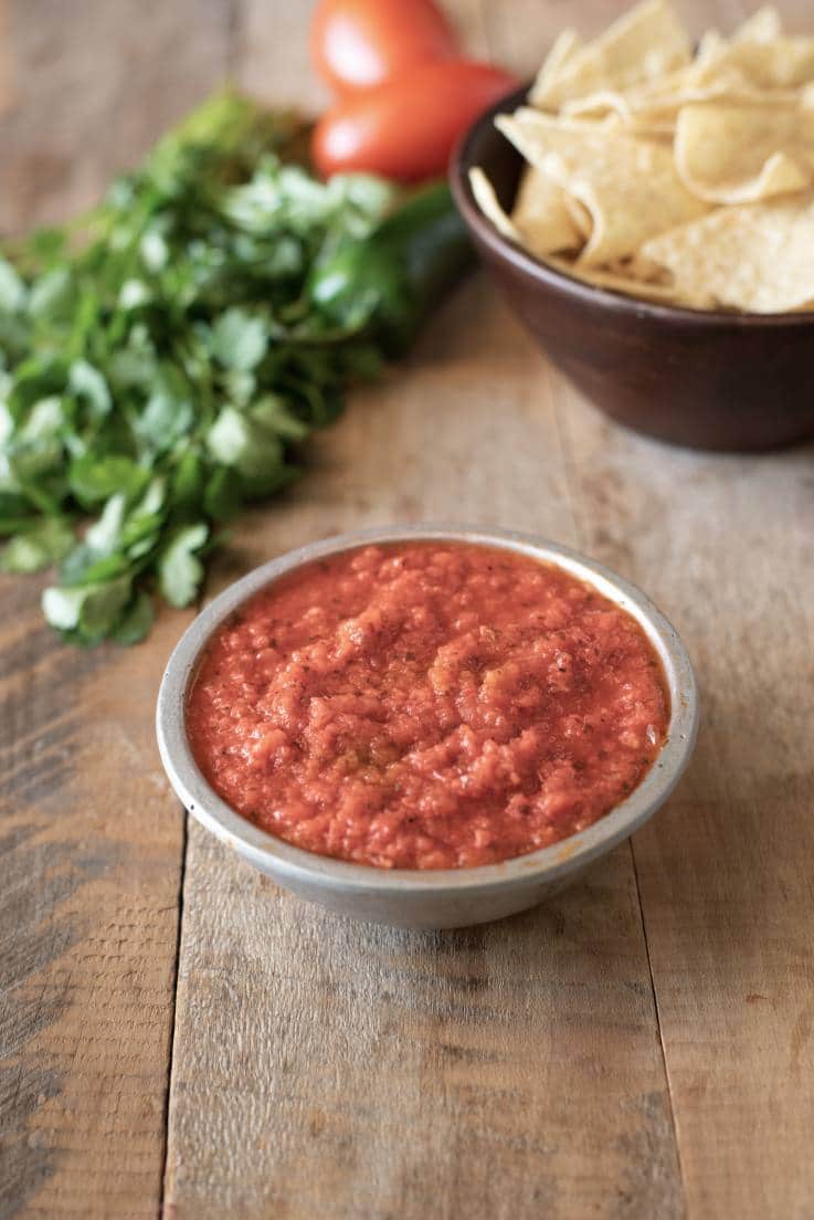 A bowl of Easy Restaurant-Style Red Salsa with tortilla chips and cilantro