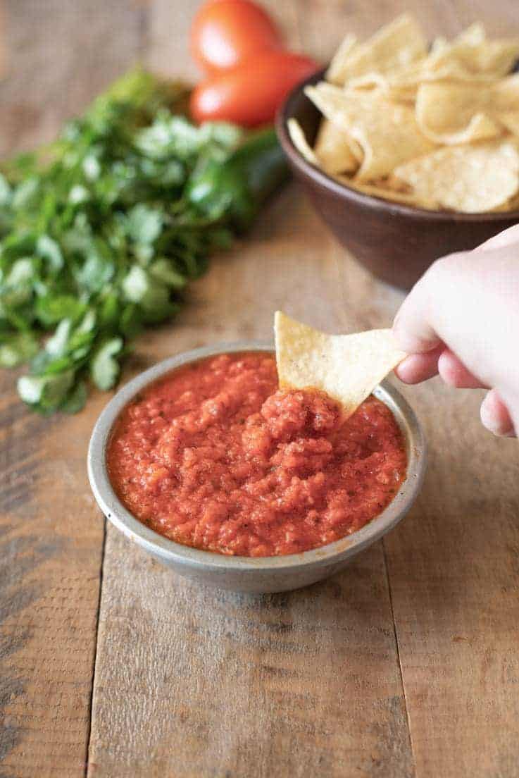A tortilla chip being dipping to Easy Restaurant-Style Red Salsa