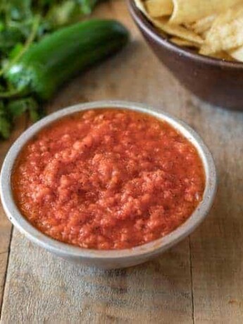 A bowl of Easy Restaurant-Style Red Salsa with cilantro and tortilla chips