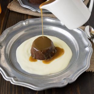 Sticky toffee pudding and English custard on a plate with toffee sauce