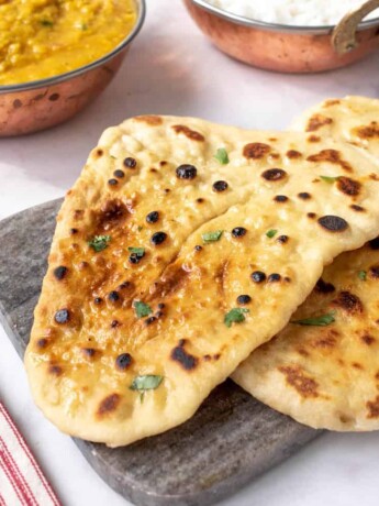 A closeup of 2 naan breads in a cutting board