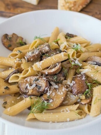 Dinner is served pasta, mushrooms, fennel and sage in a white bowl