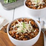 Turkey chili in a white bowl topped with grated cheese and cilantro
