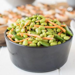 Edamame and snap peas piled high in a black bowl