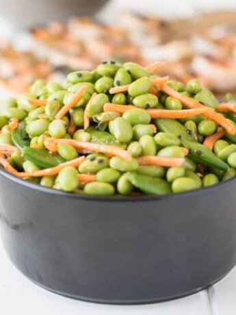 Edamame and snap peas piled high in a black bowl