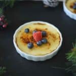 A ramekin filled with eggnog creme brûlée, raspberry and blueberries