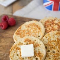English crumpets lined up on a board topped with butter
