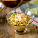 Fresh corn topped with with chili lime mayo in a glass bowl