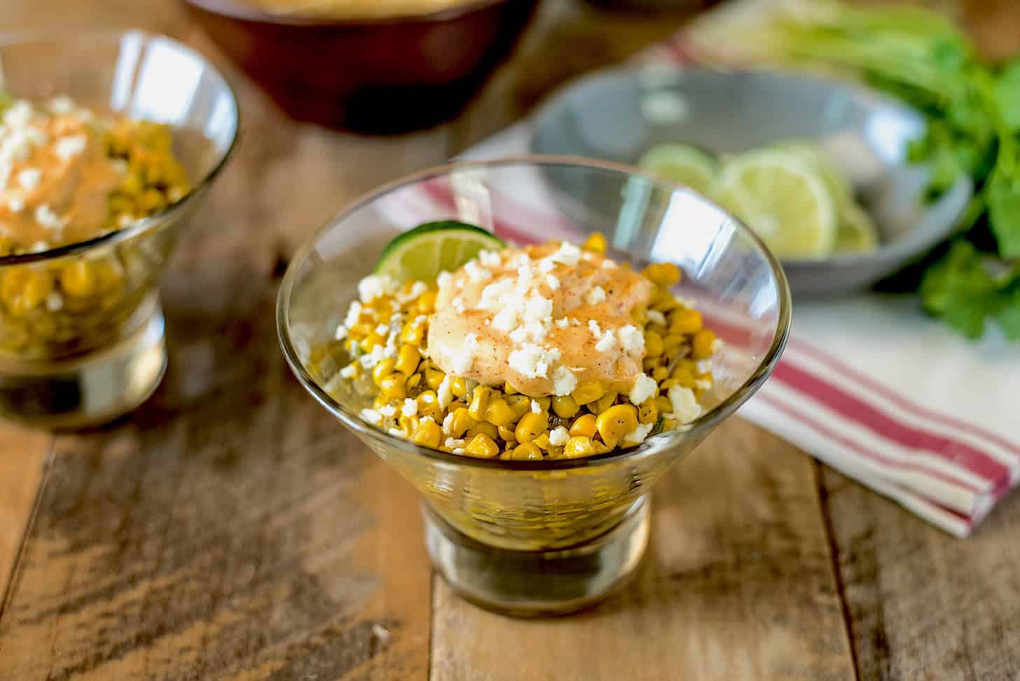Fresh corn topped with with chili lime mayo in a glass bowl