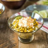 Esquites Mexican Street Corn Salad in a glass bowl with fresh limes