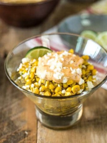 Esquites Mexican Street Corn Salad in a glass bowl with fresh limes