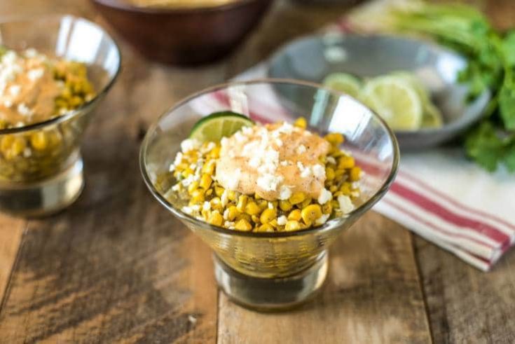 Esquites Mexican Street Corn Salad in a glass bowl with fresh limes