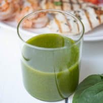 Vibrant green herb sauce in a glass storage jar