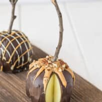 A green apple decorated with chocolate on a board