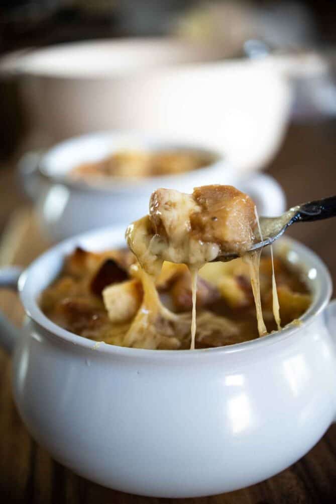 A spoonful of French onion soup with crouton and melted cheese