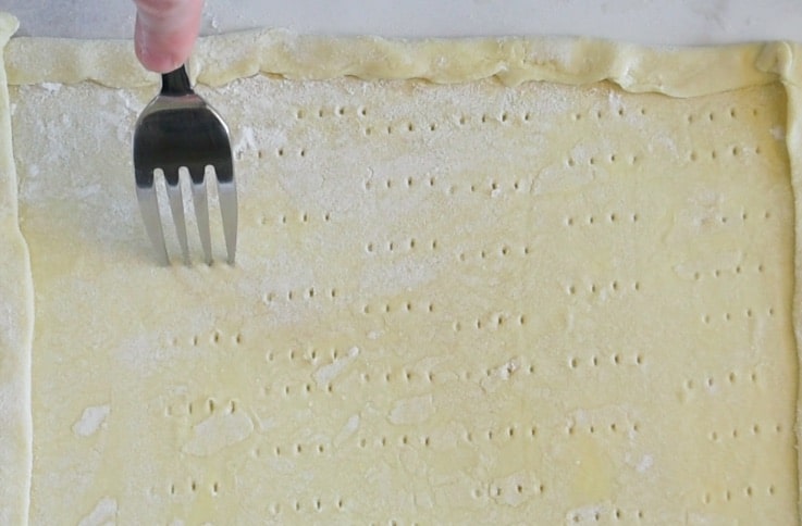 Poking holes with a fork into the puff pastry