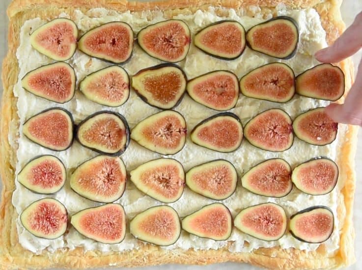 Fresh fig slices are arranged on top of the ricotta and tart