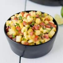 A black bowl filled with fresh pineapple salsa