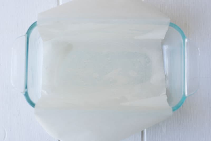 A glass loaf pan lined with parment paper