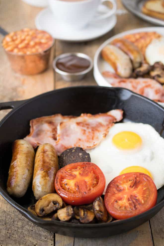 Sausages, tomato, mushrooms, bacon and egg in a cast iron skillet