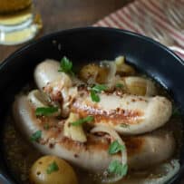 Pale Weisswurst German sausages in a bowl with potatoes and onions