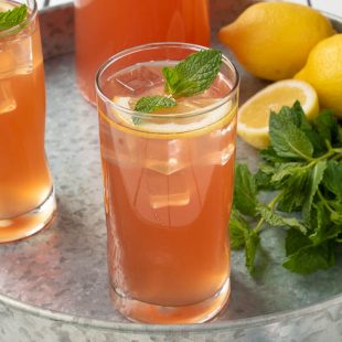 Ginger mint lemonade in a glass garnished with lemon and fresh mint