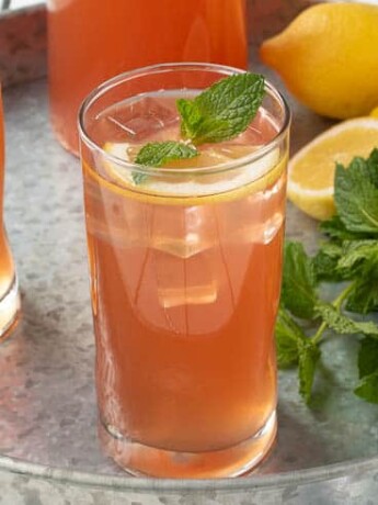 Ginger mint lemonade in a glass garnished with lemon and fresh mint