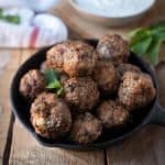 A black skillet full of browned meatballs