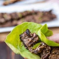 Pieces of grilled beef inside a lettuce leaf with sesame seeds and sliced scallion