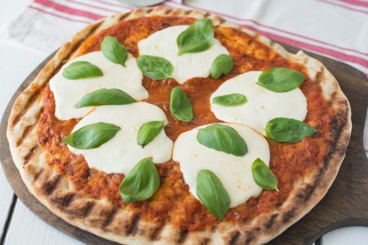 Perfect grill marks on the crust of this pizza with sauce, mozzarella and basil