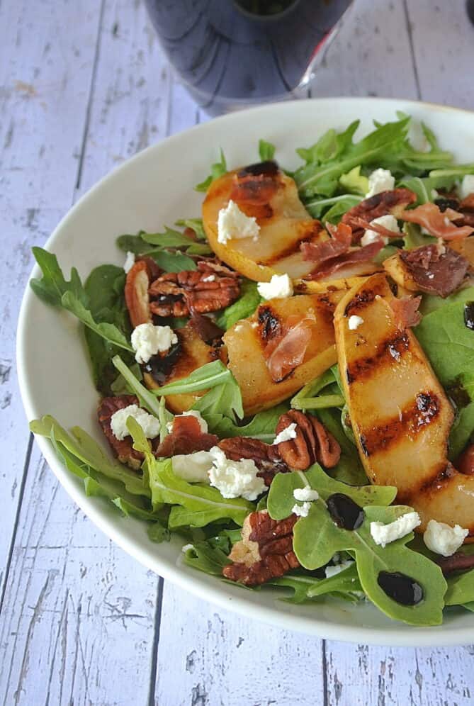 A closeup of a grilled pear slice on a salad