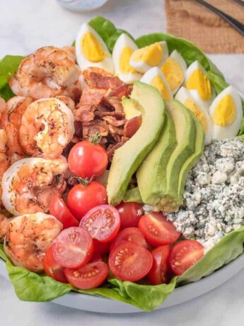 Grilled shrimp, tomato, bacon, avocado, egg and blue cheese on top of lettuce make up this grilled shrimp cobb salad