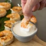 dipping a grilled shrimp into a white sauce