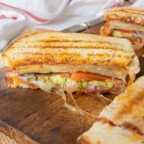 Grilled summer vegetable panini on a cutting board cut in half
