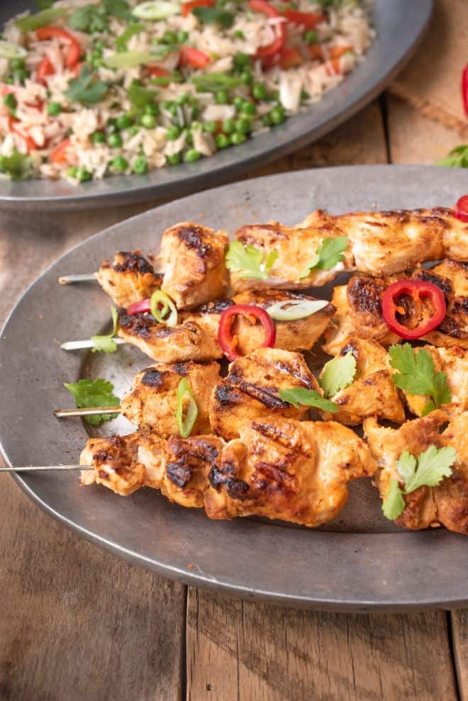A closeup of Grilled Thai Chicken Kabob Skewers garnished with green onion and red peppers