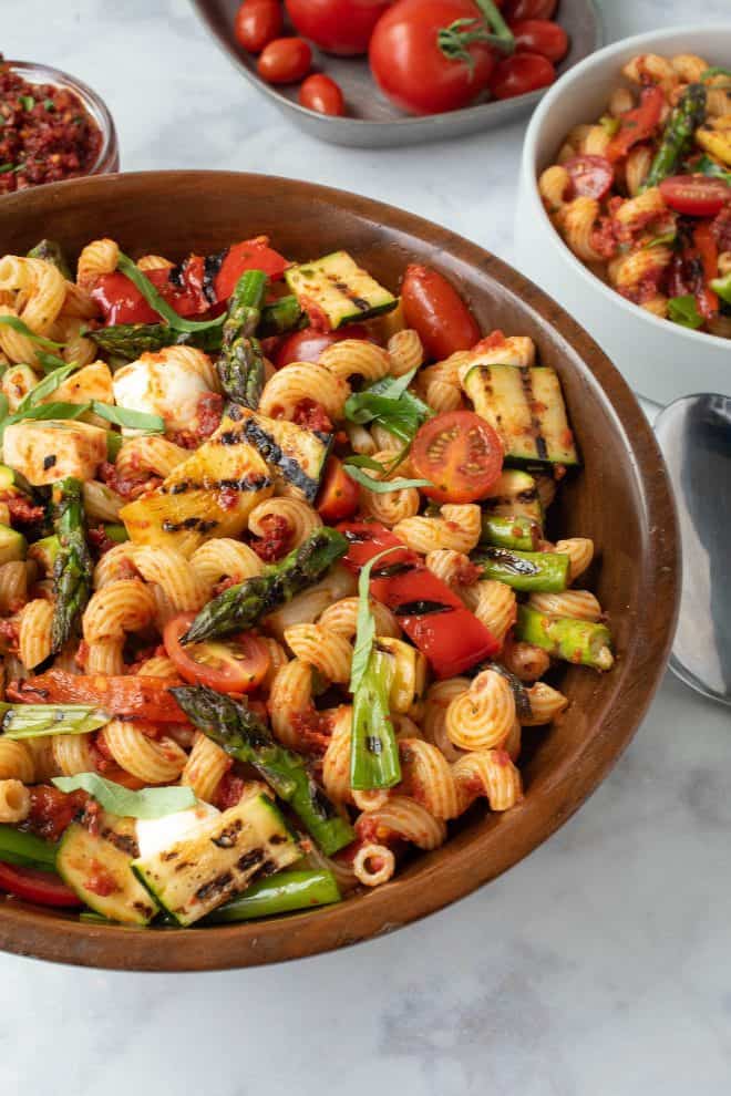Colorful grilled vegetables in a wood bowl of pasta mixed with sun-dried tomato pesto