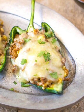 Grilled beef stuffed poblano peppers on a silver plate